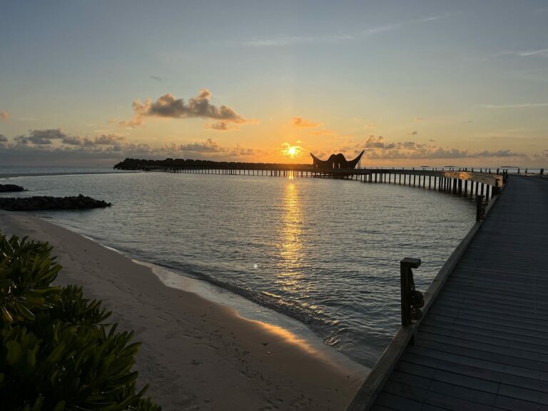 Sunset over a curved jetty and overwater villas, Maldives